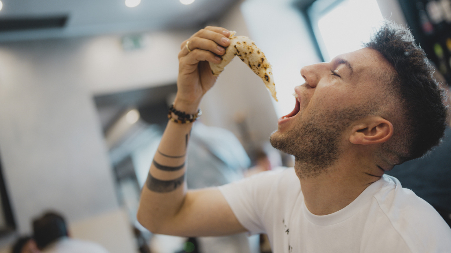 Angelo Tortora vom Restaurant Mamma Lina isst ein Stück neapolitanische Pizza – Szene aus der Produktion des preisgekrönten Pizzabuchs Pizza con Amore vom Tietge Verlag.