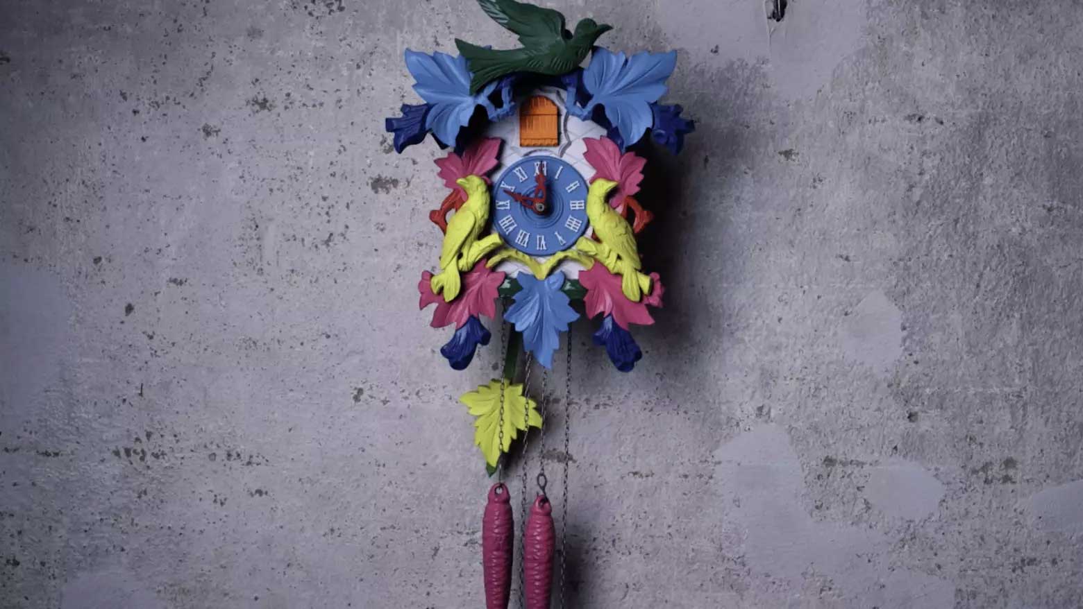 Bunte Kuckucksuhr, die an einer grauen Wand hängt